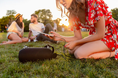 company of friends having fun together in park listening to music
